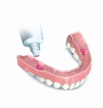 putting adhesive cream on lower dentures