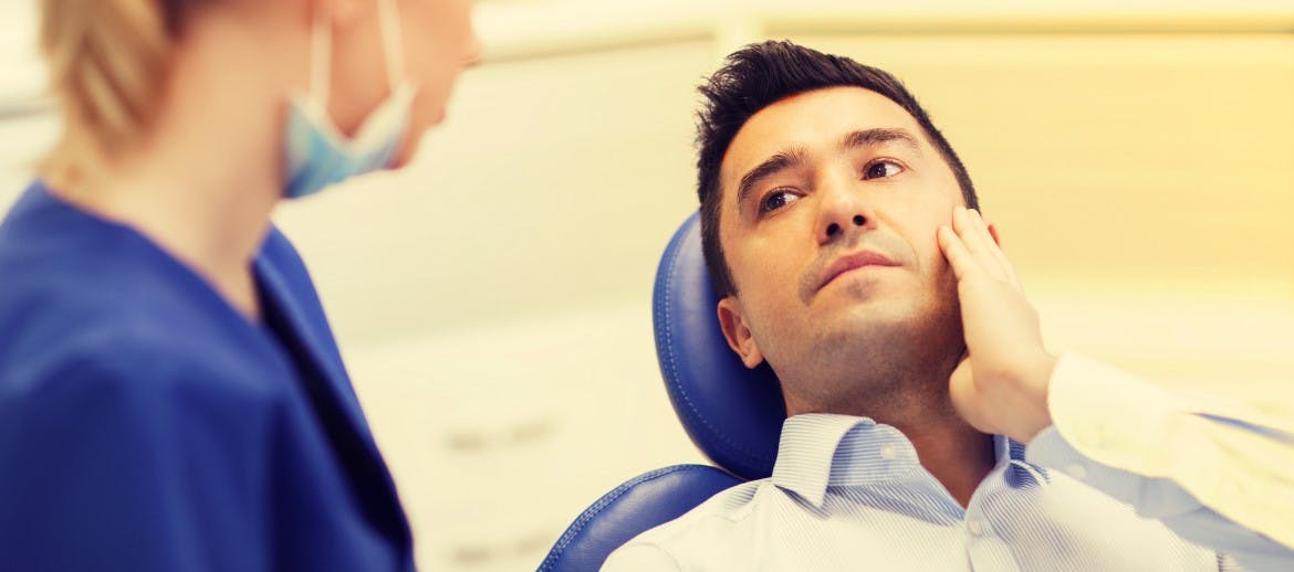 A man holding his face in pain at dentist