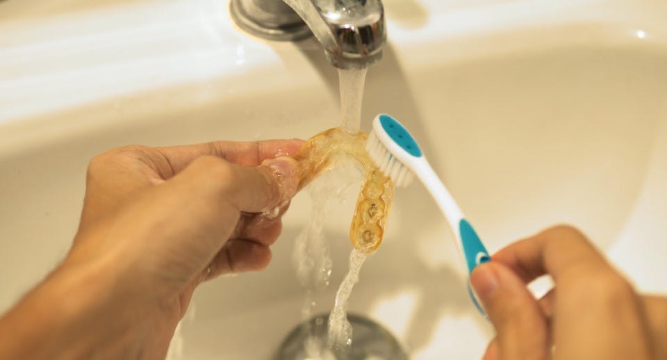 toothbrush cleaning a retainer under water