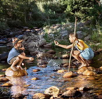 Παιδιά που κάθονται σε πέτρες στο ποτάμι