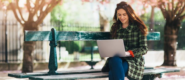 Femeie cu laptop pe banca Femeie cu laptop pe banca