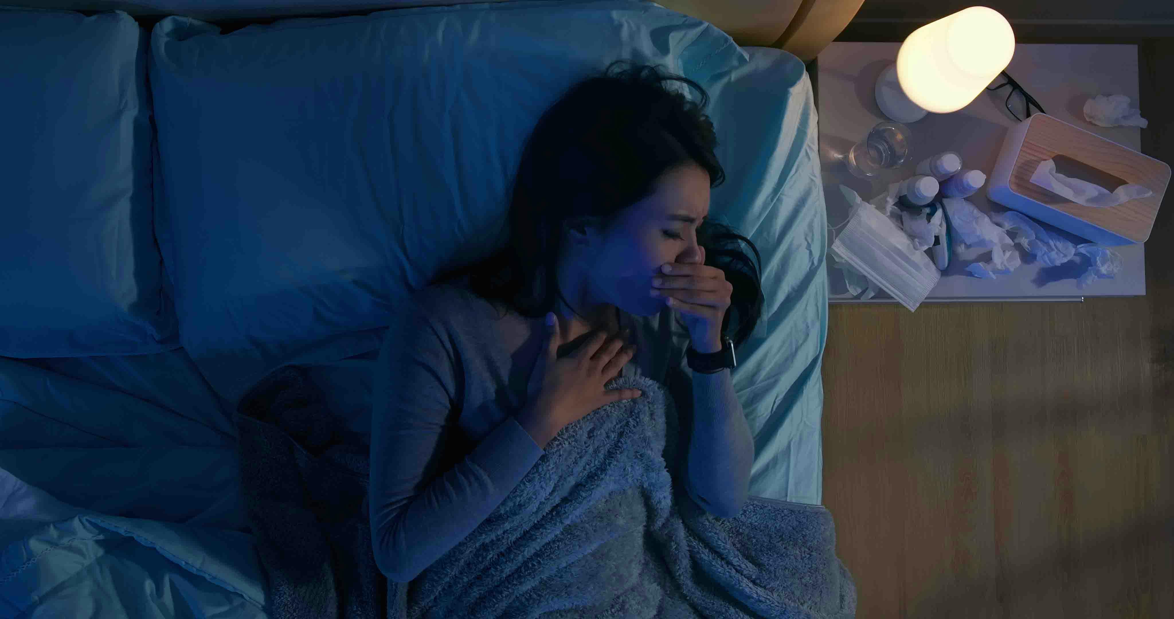 Woman sneezing in bed at night