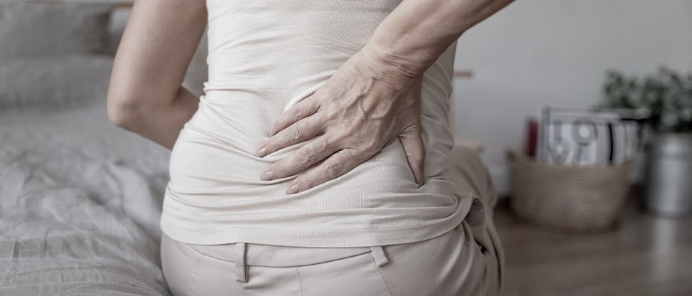 Patient mit Rückenschmerzen hält sich die Hand an eine schmerzende Stelle