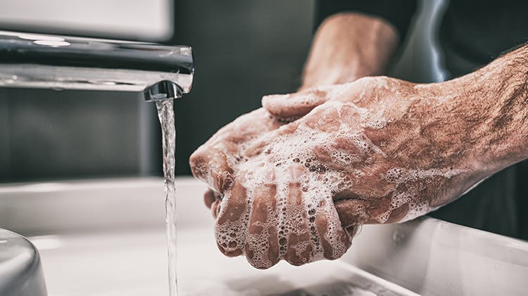 Eine Person wäscht sich in einem Waschbecken die Hände mit Seife.