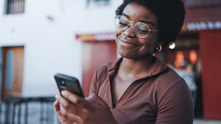 Eine Frau erhält auf ihrem Mobiltelefon eine SMS und lächelt