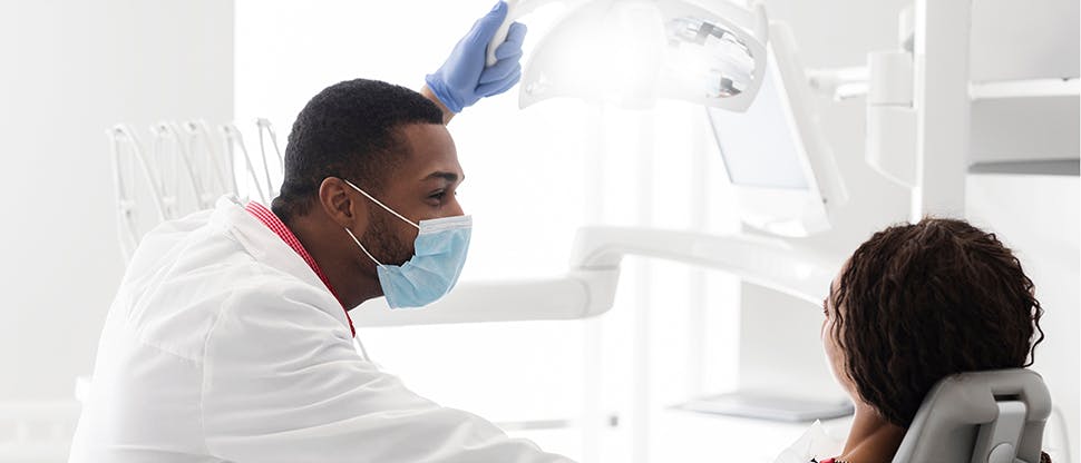 Άνδρας οδοντίατρος που μιλάει σε ασθενή για τους κινδύνους της ουλίτιδας και τη σημασία της καθημερινής αφαίρεσης οδοντικής πλάκαςst