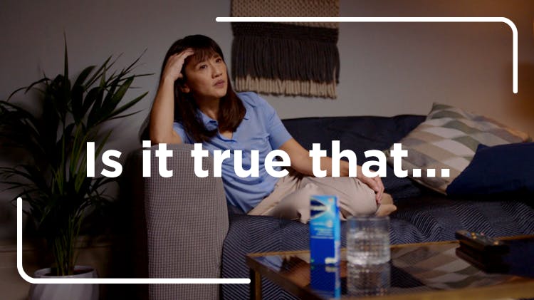 Μια μελαχρινή γυναίκα ξαπλώνει στον καναπέ, πιθανώς νιώθοντας πονοκέφαλο ή σωματικό πόνο, ενώ ένα προϊόν Panadol βρίσκεται στο τραπεζάκι του σαλονιού σε πρώτο πλάνο.