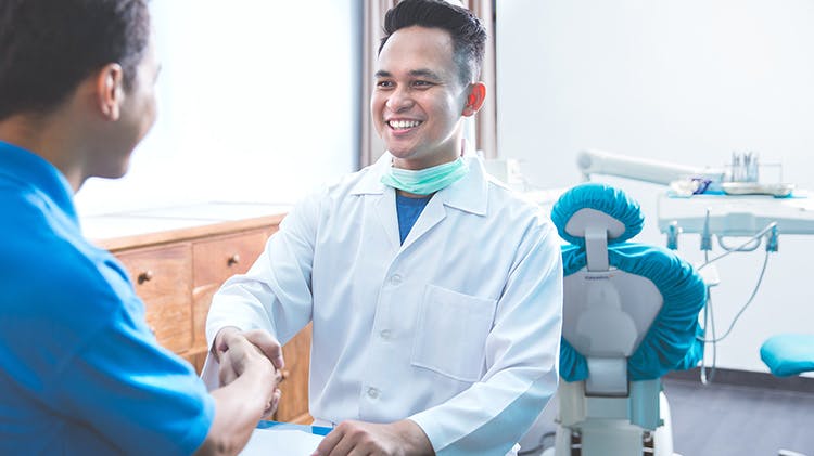 A dentist shakes hand with patient