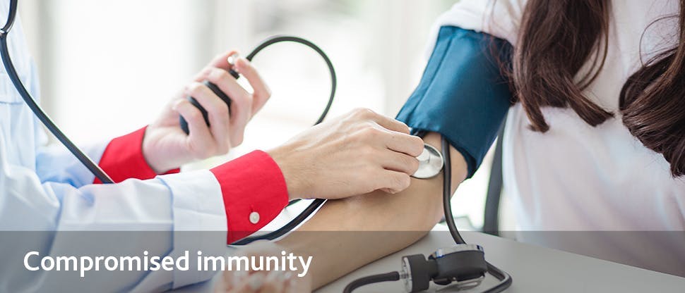 The gloved hand of a healthcare professional performs a finger prick test on a patient.