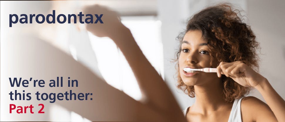 Young woman with curly brown hair looks in the mirror while brushing her teeth. Text overlay says: ‘paradontax. We’re all in this together: part 2.’