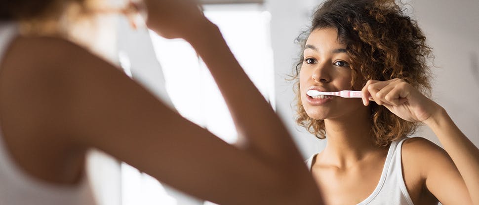 Woman brushing teeth in the mirror