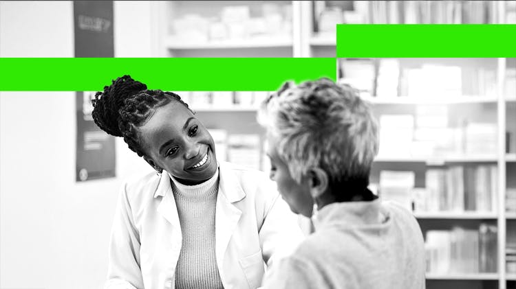 A young female pharmacist smiles while talking to an older female patient