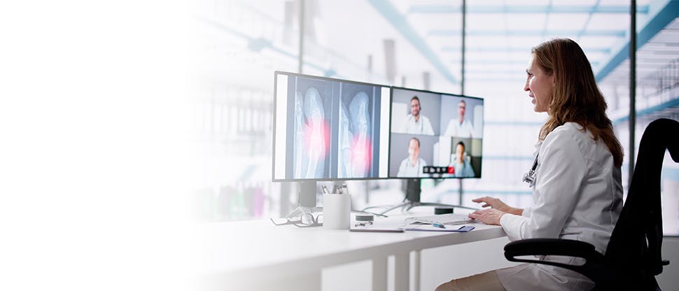 A female doctor is sitting & attending call with other doctors