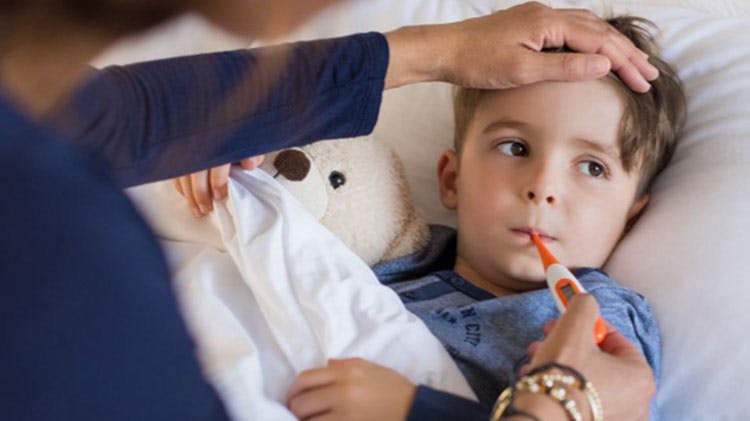 Woman comforting a child with a  headache, testing his temperature with  a thermometer