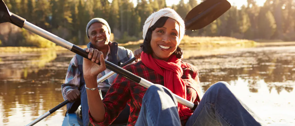 Image showing a man and woman smiling and sat on a boat holding oars.