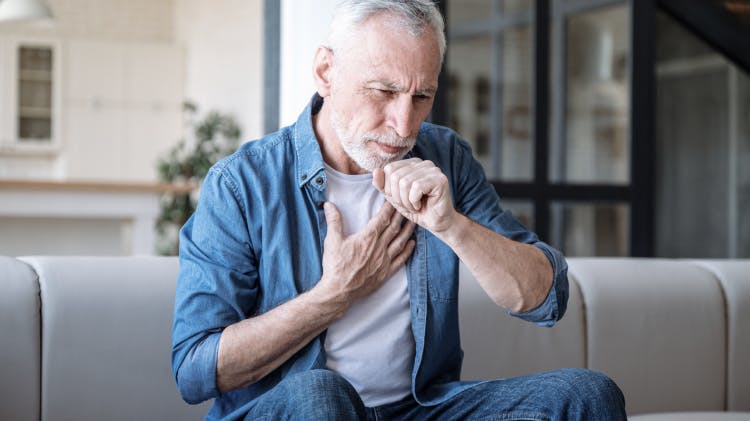 Mature male adult coughing while holding his chest
