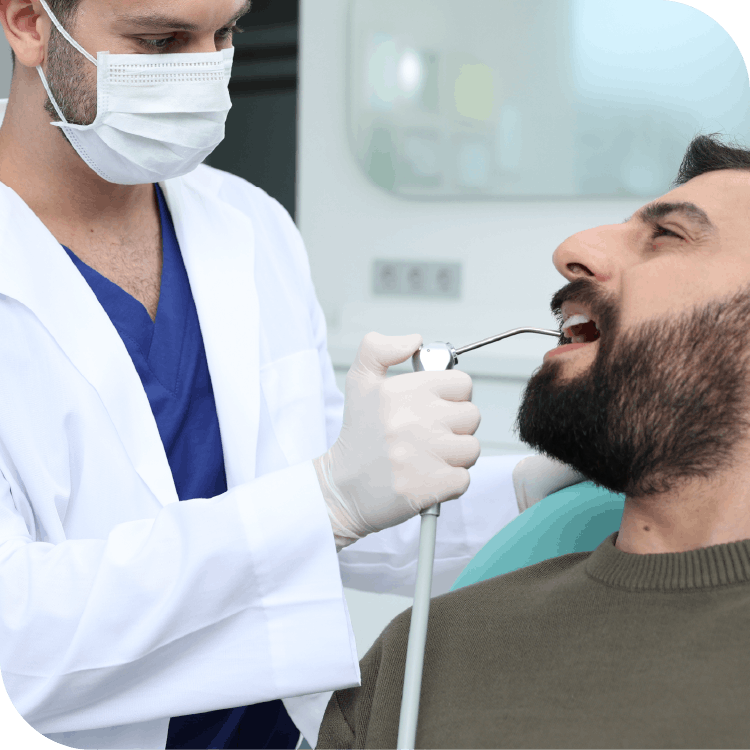 Turkish or African dentist using air probe on patient