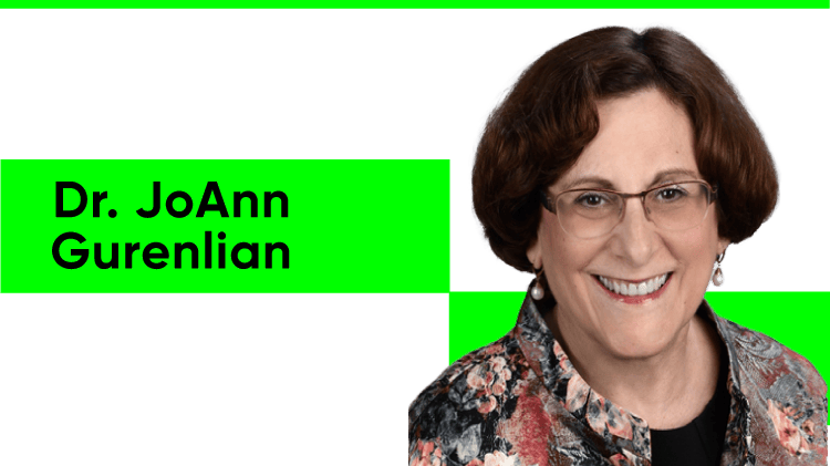 Headshot of Dr JoAnn Gurenlian, a white woman with short brunette hair worn in a bob. She wears glasses, pearl drop earrings and a floral-patterned shirt over a black top.
