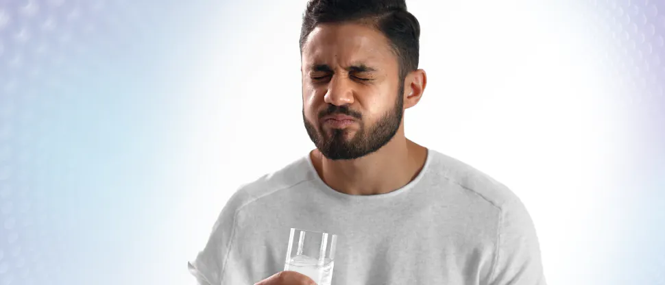 Image of a young male patient drinking iced water and reacting to painful sensitive teeth