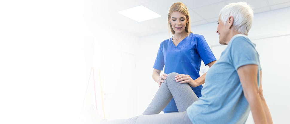 Female doctor is helping aged patient with physical exercise