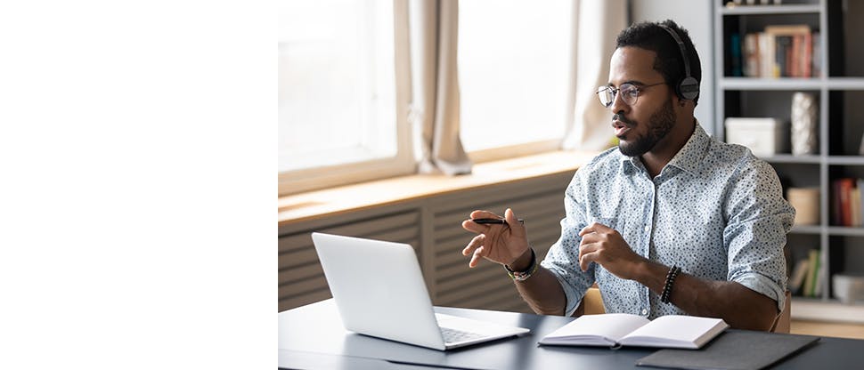 A man wearing headphones taking an online call on a laptop