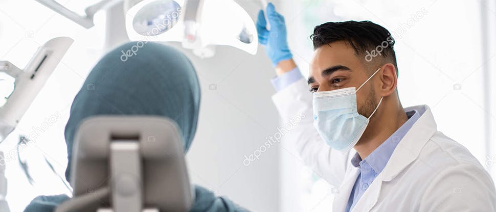 A male dentist discusses the risks of gum disease and the importance of daily plaque removal with a patient.