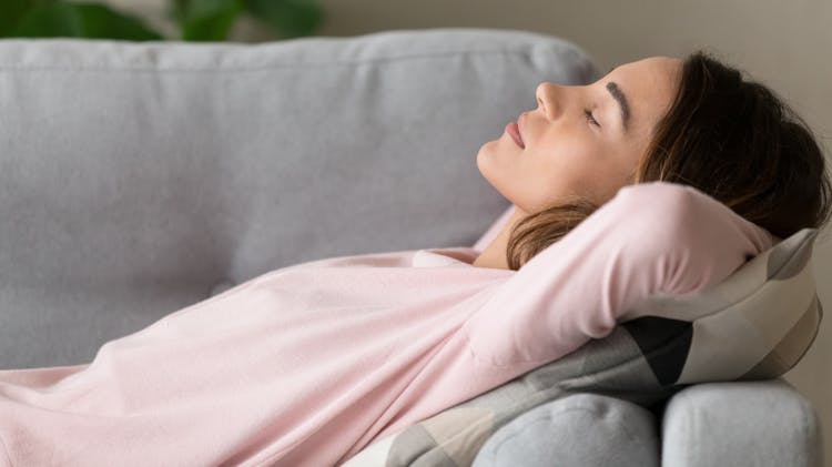 Young woman relaxing on the sofa with hands behind her head
