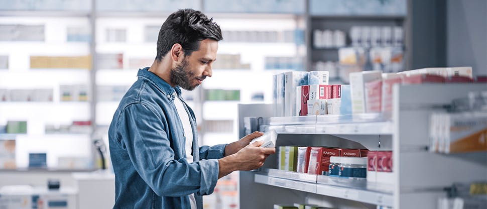 A man selects an item from a shelf in a pharmacy.