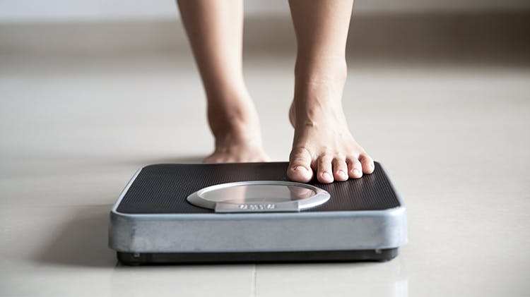 Two feet on a weighing scale on the floor.