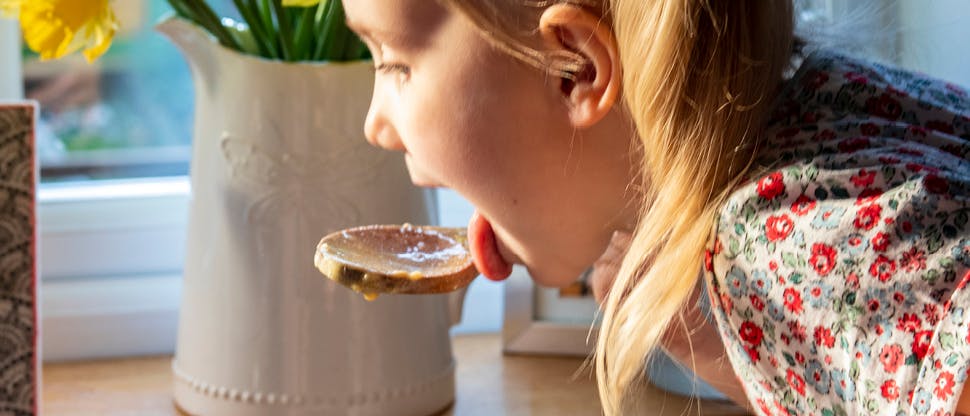 Image of girl eating cake mix from a wooden spoon