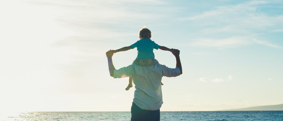 Man with a child on his shoulders at the beach