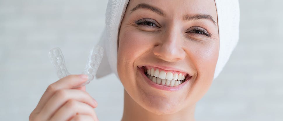 Smiling patient holding her removable retainer