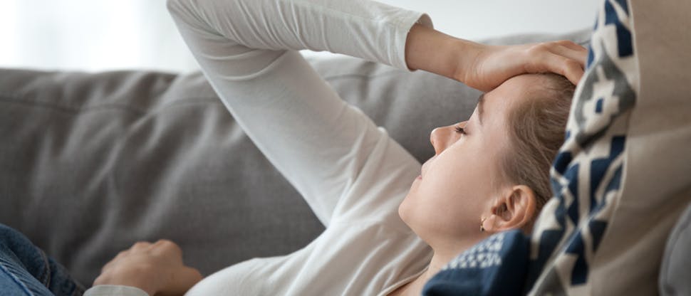 Image of a woman holding her head lying on a sofa