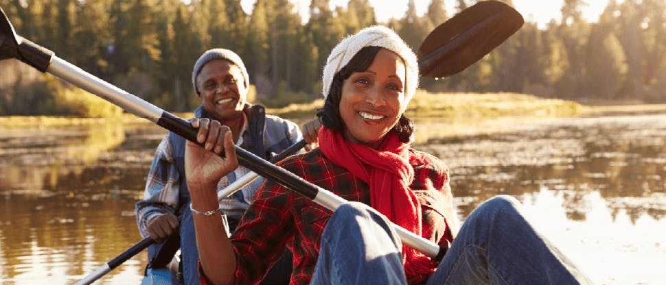 Image showing a man and woman smiling and sat on a boat holding oars.