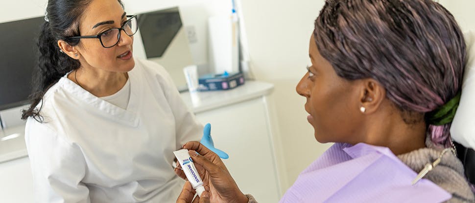 Image of a dental professional handing a sample of Sensodyne toothpaste to a patient
