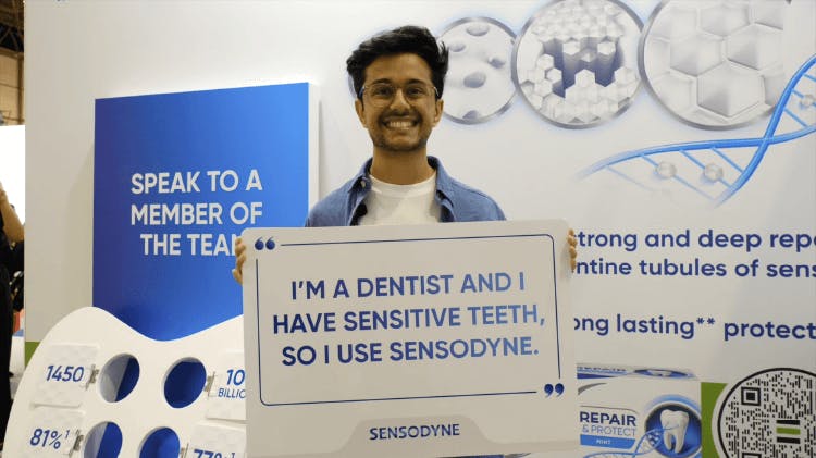 Image of man holding a sign which says ‘I am a dentist and I have sensitive teeth, so I use Sensodyne’