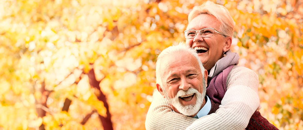 An older man and woman smile happily with their new dentures. 
