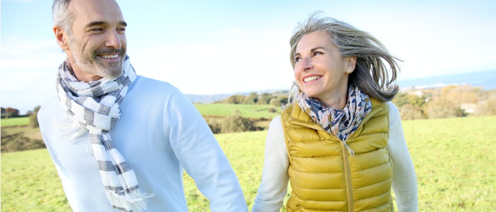 Older man and woman holding hands while walking