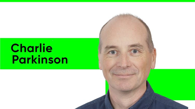 Charlie Parkinson, a man with short dark hair and dark eyebrows. He wears a black shirt