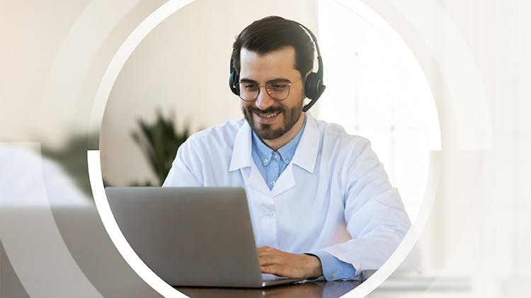 A pharmacist works happily at a computer.