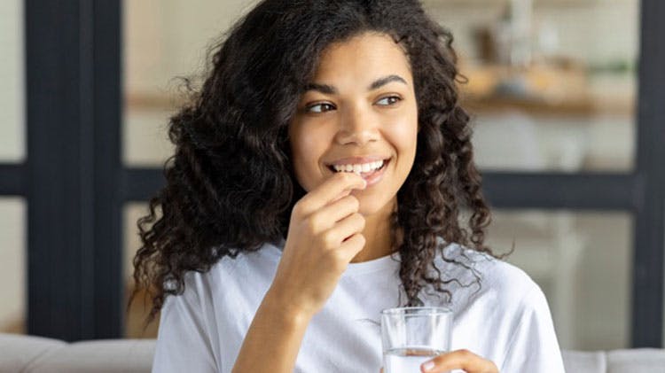 Woman taking a Panadol paracetamol product for pain relief 