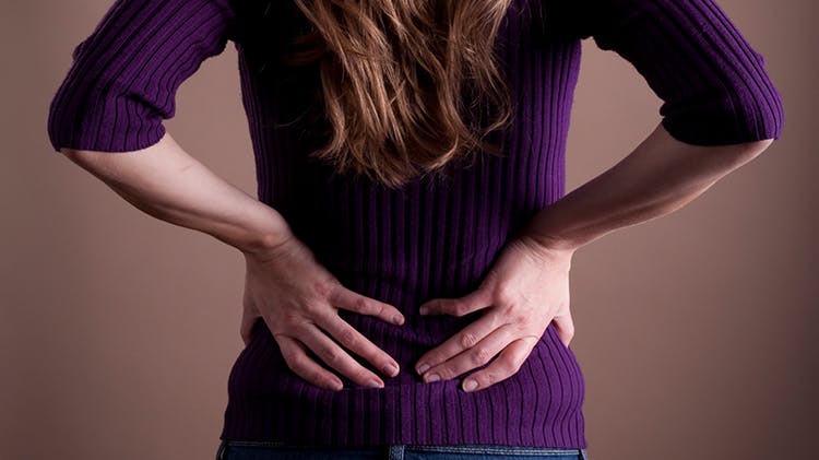 Woman holds lower back in pain Woman holds lower back in pain