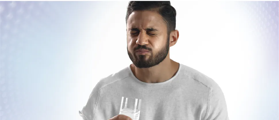 Image of a young male patient drinking iced water and reacting to painful sensitive teeth