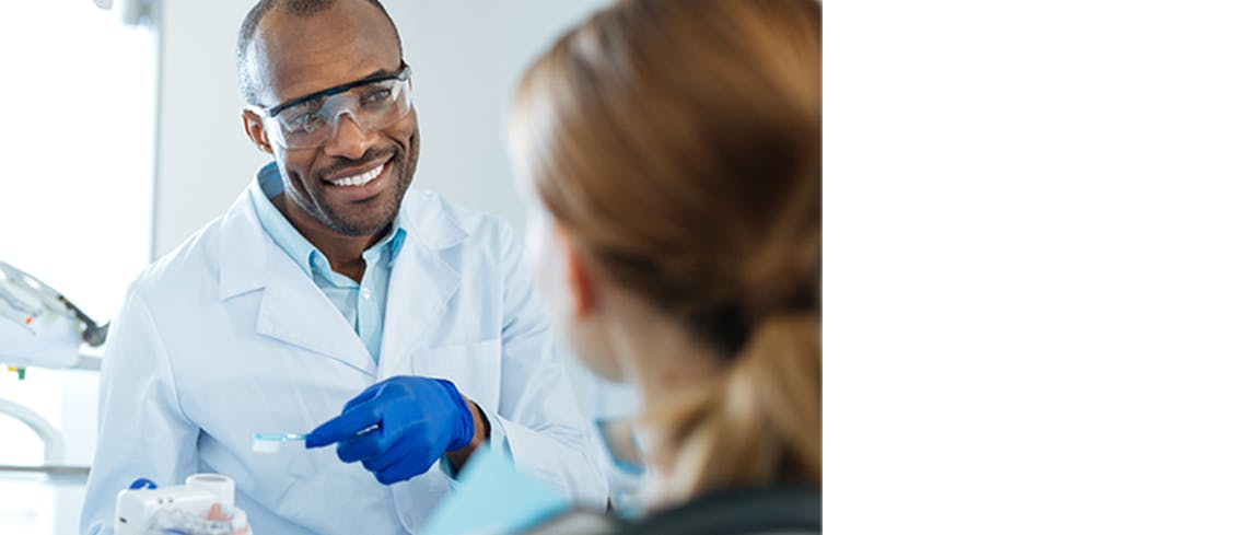 Dentist holding a toothbrush to demonstrate proper brushing