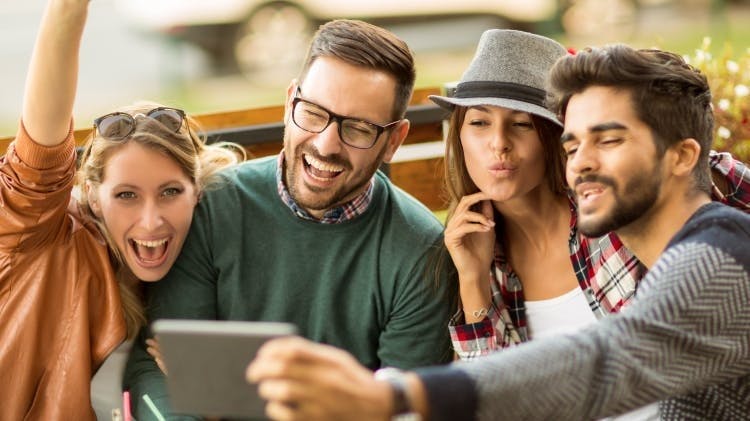 A group of friends laugh and smile together, showing clean, white and healthy teeth.
