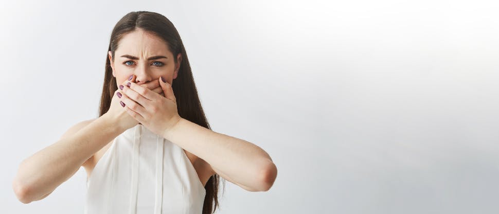 Woman covering her mouth embarrassed of her bad breath