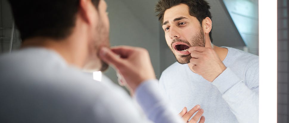 An image of man looking at gums in mirror