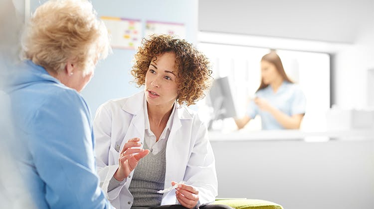 A doctor explains medical information to an older female patient.