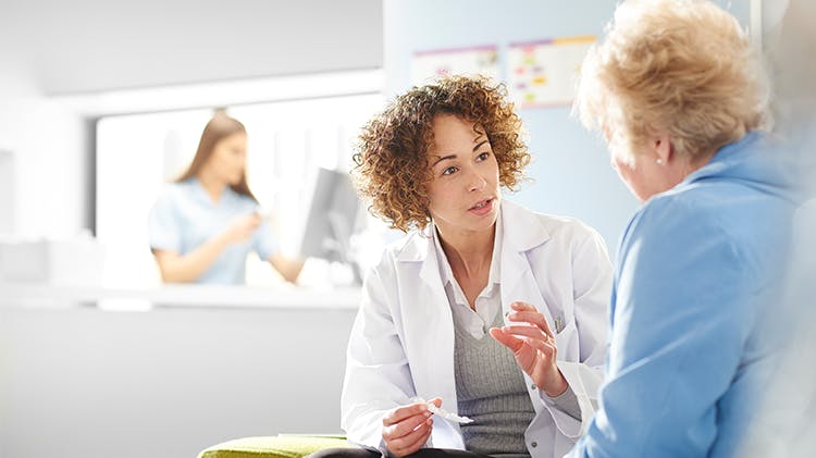 A doctor explains medical information to an older female patient.