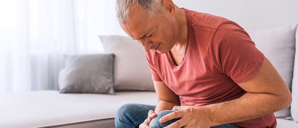 Man clutching knee in pain